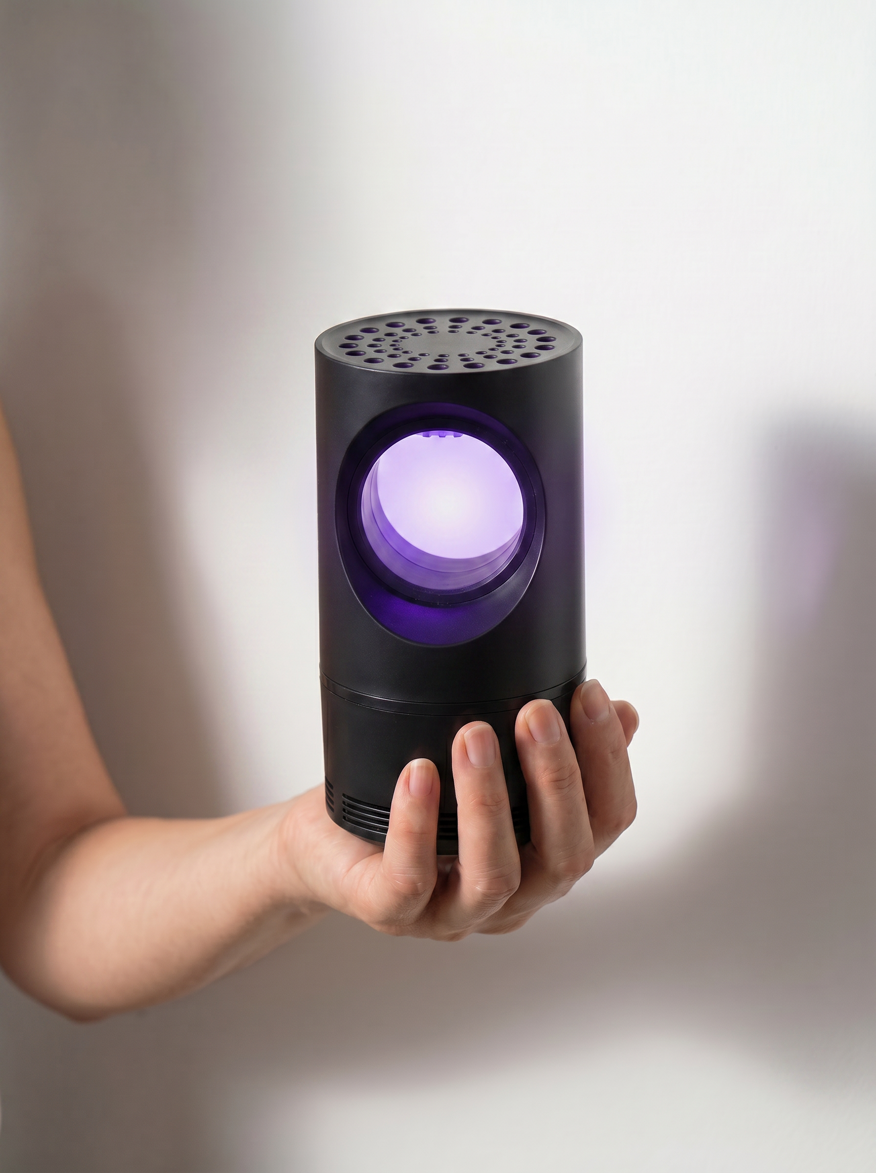 Hand holding the Black MousKill mosquito killer lamp showing its compact size